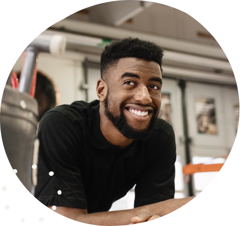 A smiling portrait of a black man resting on his elbows, looking into the distance.