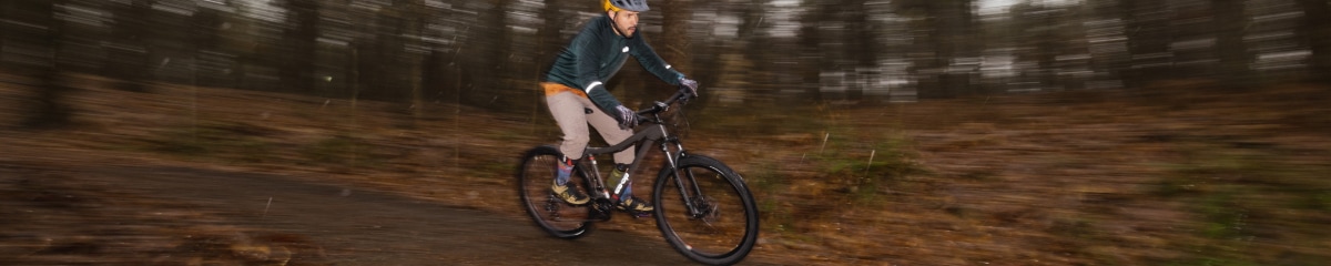 A mountain biker riding on a wooded trail.