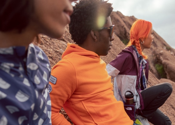 Three hikers sitting on a desert trail and looking off in the distance.