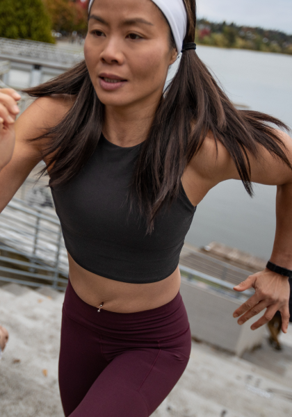 A runner in athletic apparel sprints up stairs by a lake