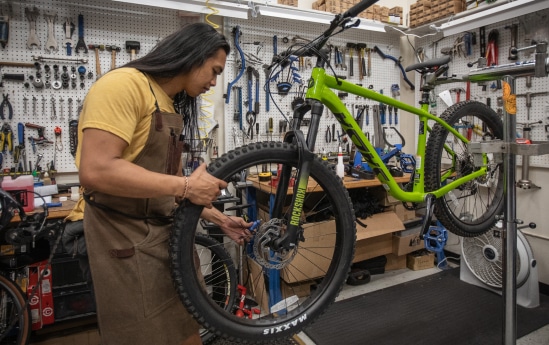 A cycle shop technician adjusts a wheel.