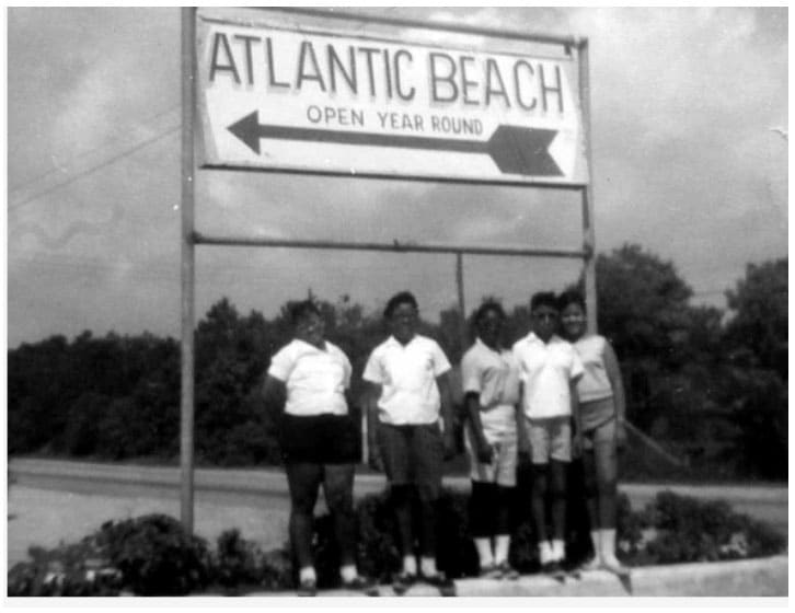 A group standing in front of a sign labelled Atlantic Beach