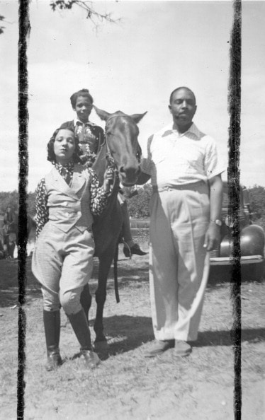 A woman and man standing next to a horse