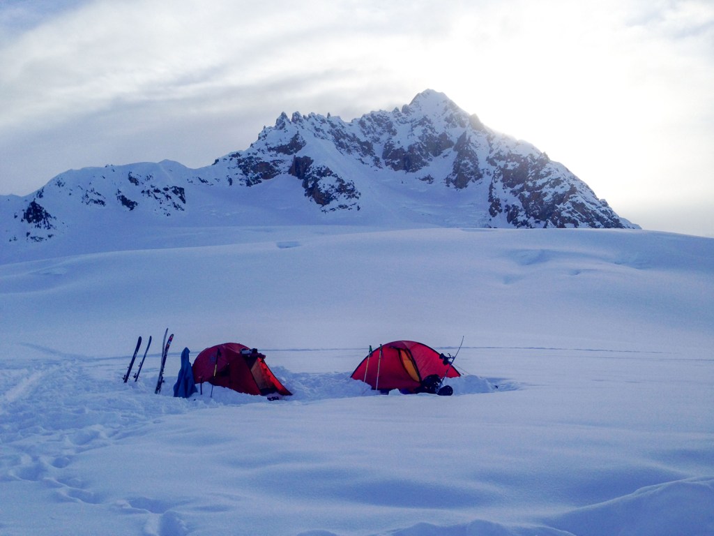 snow camping at the base of a mountain in a field of snow.