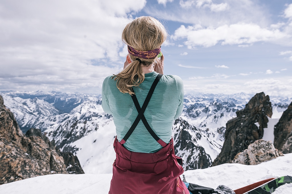 woman standing on a mountain looking over a snowy mountainous landscape