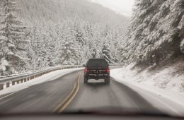 truck driving a winter road through snow covered trees