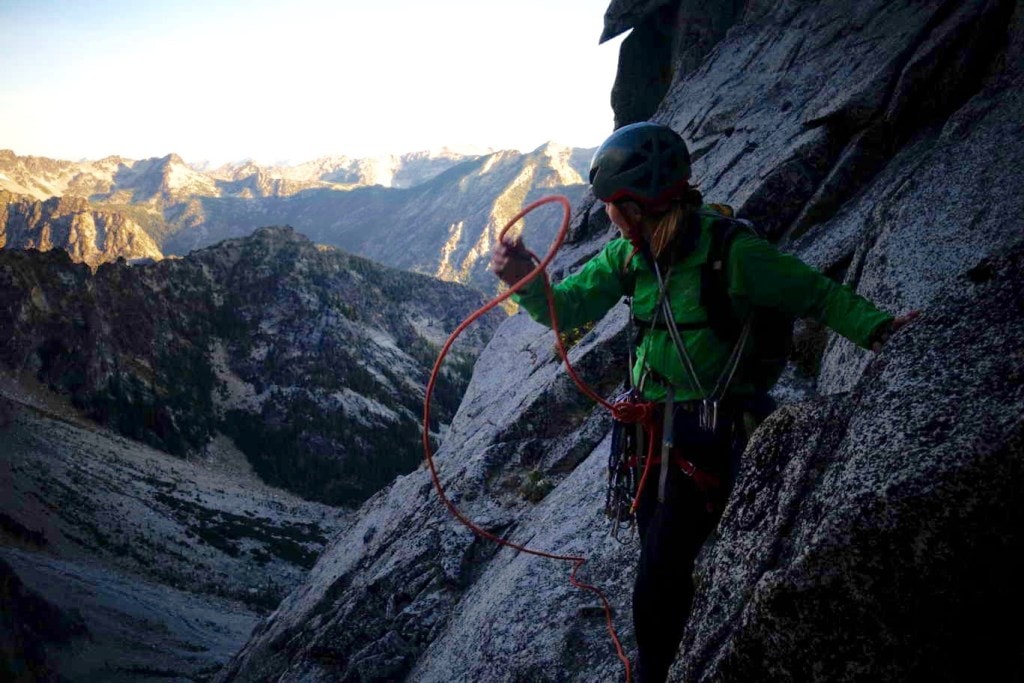 female flakes rope high on a rock wall