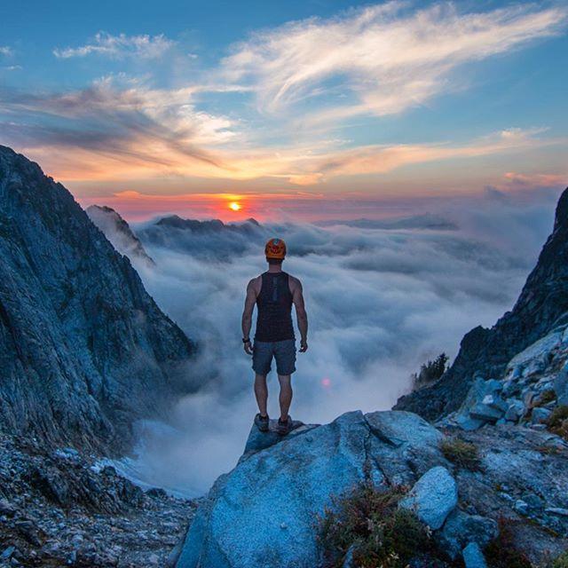 rock climber standing above clouds