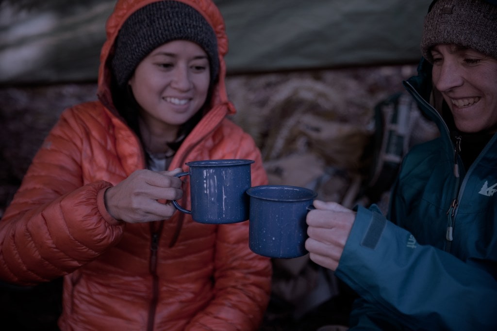 two campers toasting with warm beverages