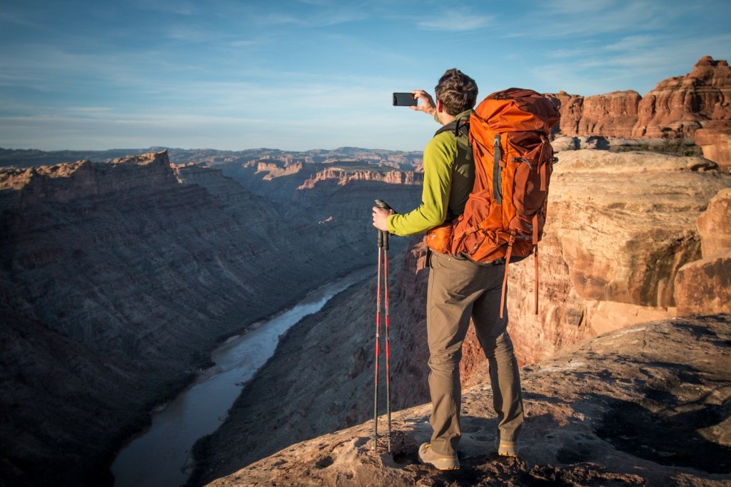 man standing on mountain lookout wearing Osprey Aether 60