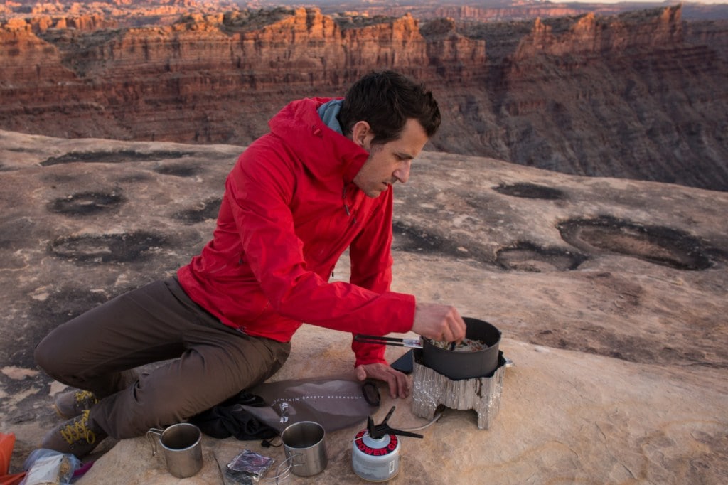 man cooking dinner wearing Outdoor Research Axiom Jacket 