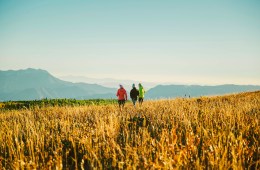 women standing in a grassy field surrounded by mountains at REI Outessa