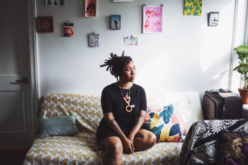 Illustrator Loveis Wise sitting on her bed.