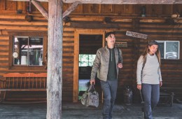 Two travelers leaving a log cabin