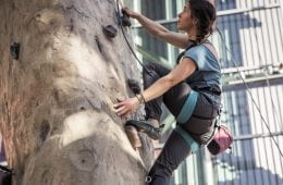 A woman climbs an indoor climbing wall on toprope.