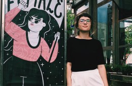 Camila Rosa is leaning against a photo booth featuring her art.