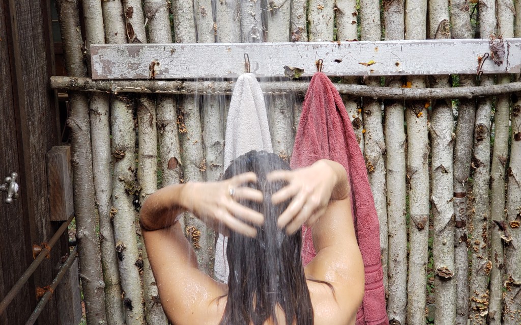 A woman's head and shoulders visible as she showers in an outdoor shower