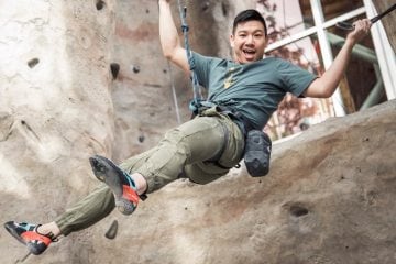 A climber lowers on a toprope, smiling at the camera.