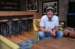 Jesse Itzler sitting on a yellow chair behind a coffee table.