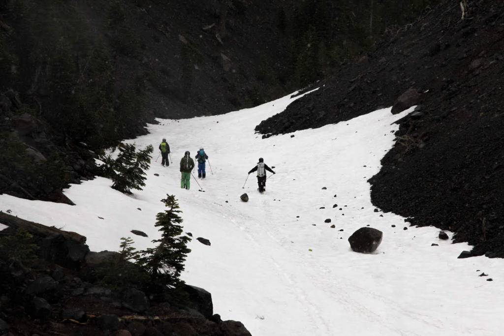 Skiers slide down a lone strip of snow.