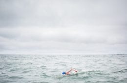 Kim Chambers swimming with a grey sky behind her.