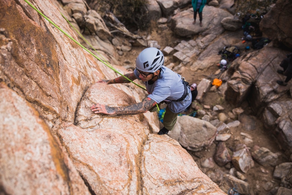 A rock climber on top-rope reaches for the next hand hold on the climbing route.