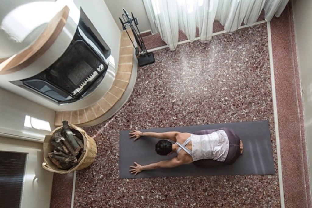 Olivia Hsu bows forward on her yoga mat with her legs tucked unerneath her in Child's Pose.