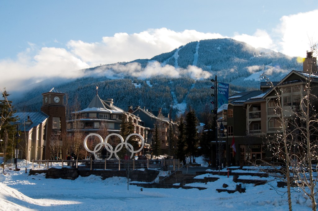 Mountain rise abruptly over a snowy Whistler Village. 