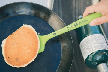 Green Alex Honnold Spatula flipping a pancake in a black pan.