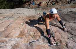 Kai Lightner reaches for a hold high above the ground while sport climbing.