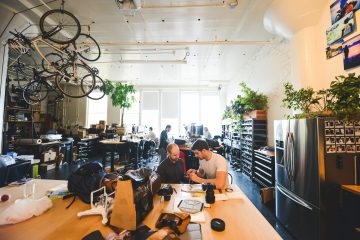 The Peak Design team works together at a desk in their office.