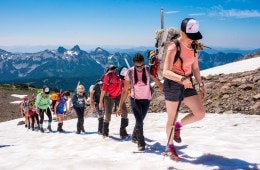 Kids climb a snow-covered mountain as a part of a youth mountaineering course with She Jumps.