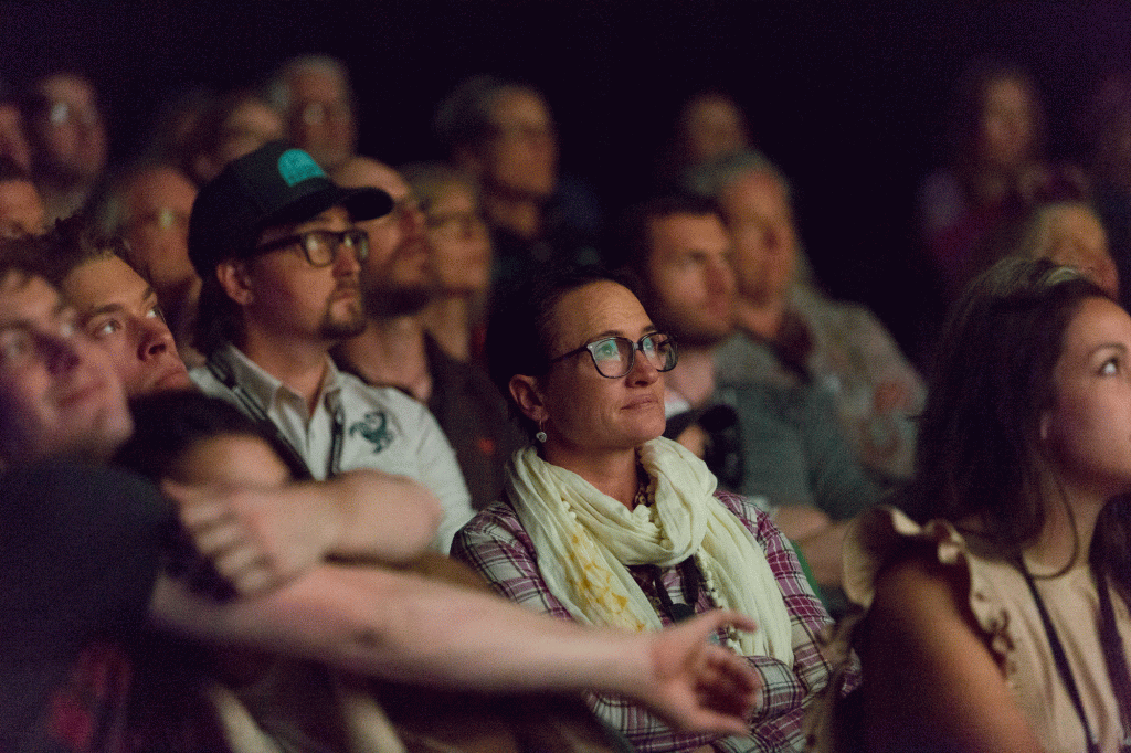 A woman watching a film with a pensive look in a darkened theater