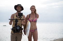 Aaron, the director of Unstoppable, standing next to Bethany Hamilton who is carrying a surfboard.