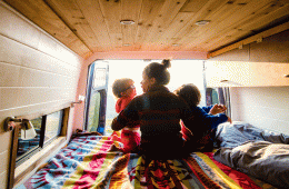 A mom snuggles with her two kids in a van