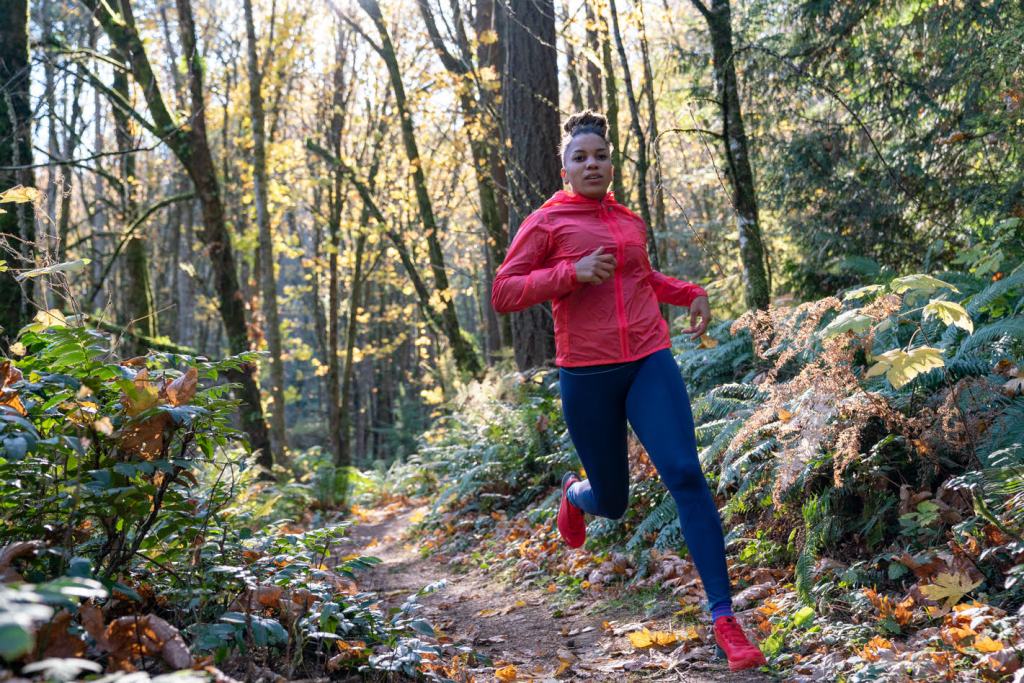 Faith Briggs runs through a forested trail.