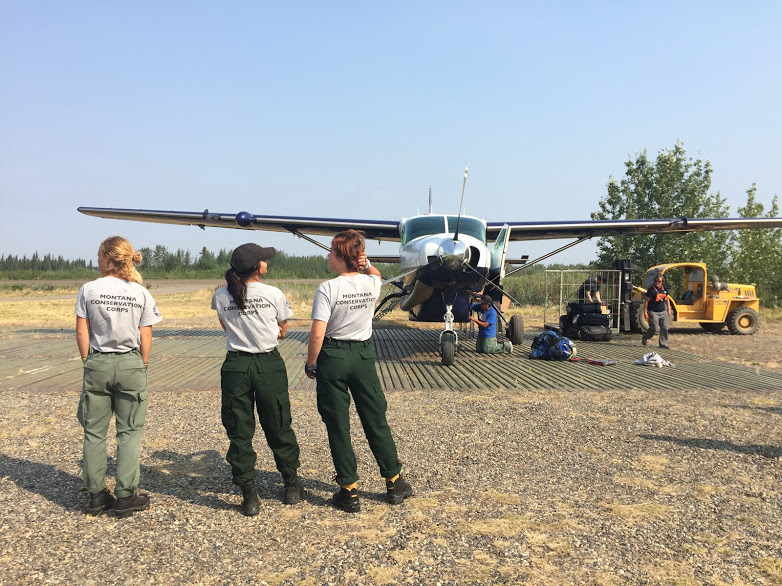 Women peer into the distance at a small plane