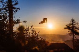 a mountain biker in mid-air from a jump with a sunset in the background at snowshoe, west virginia