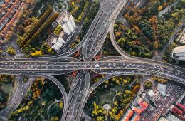 Overhead shot of highways surrounded by city forests.