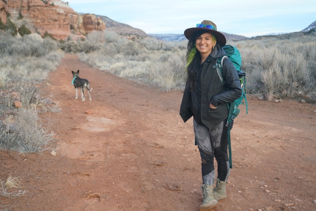 A woman smiles at the camera surrounded by sagebrush and desert