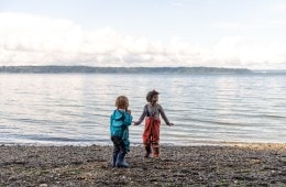 Children play by the water in waterproof overalls