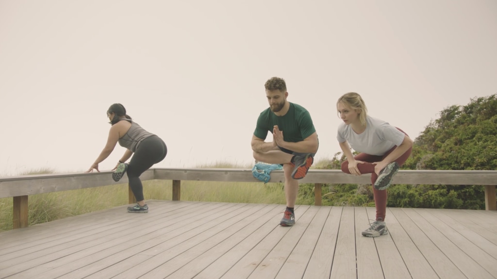 Corepower yoga instructors hold standing figure 4 pose