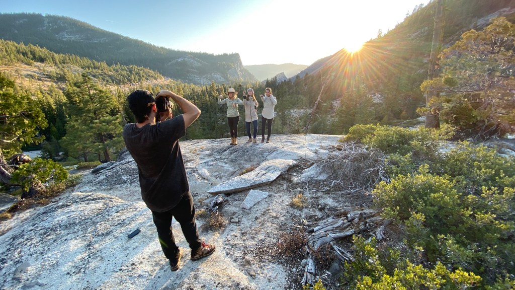 Photographer Ben Arnst takes a photo of three people hiking on a rocky outcropping.