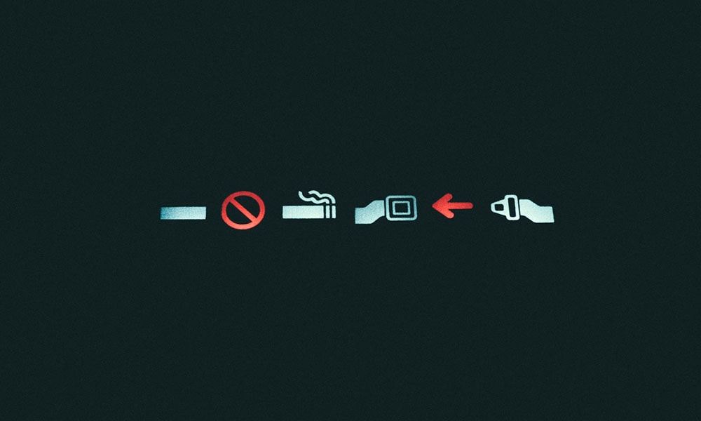 No smoking and seat belt on illuminated signs on an airplane.