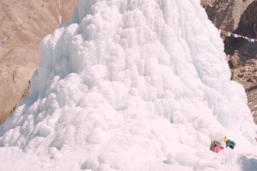 Children approach an ice stupa in the Himalaya