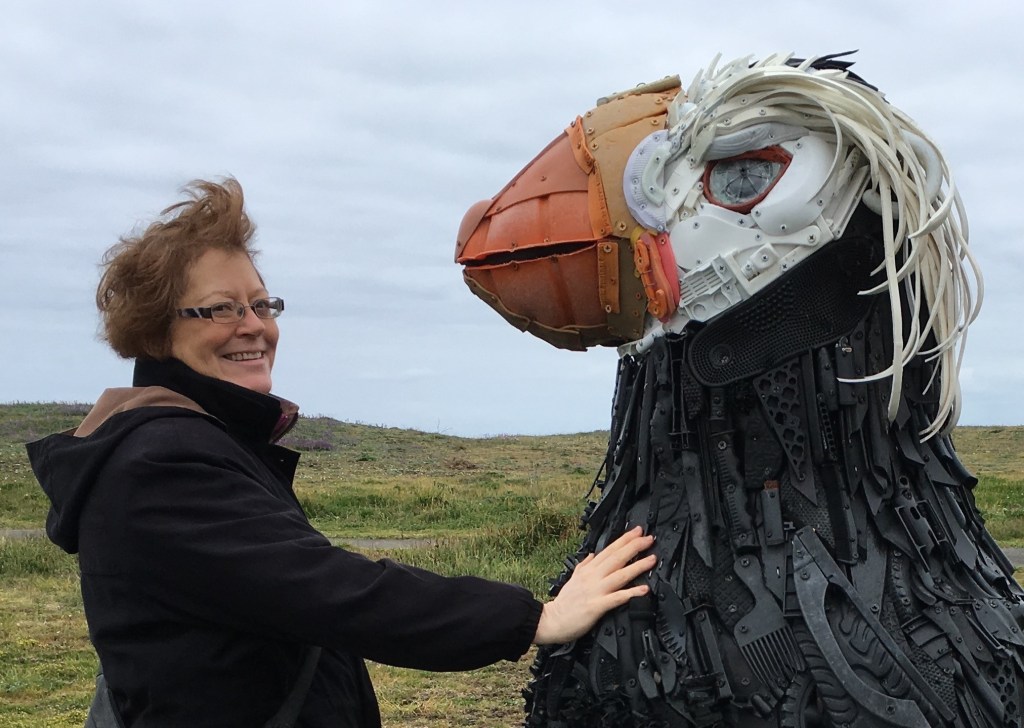 Angela stands next to Cosmo the Tufted Puffin, installed at the USFW National Wildlife Refuge at Coquille Point in Bandon, Oregon. 