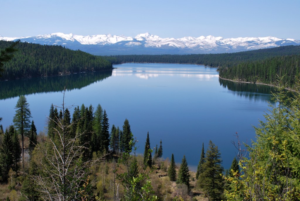 Snowcapped mountains reflect in Holland Lake waters.