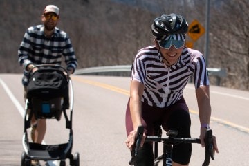 Laura King rides her bike while her husband pushes a stroller with their daughter, Hazel, behind her.