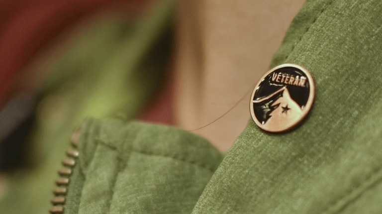 An REI store employee wears a small Veteran pin on their vest