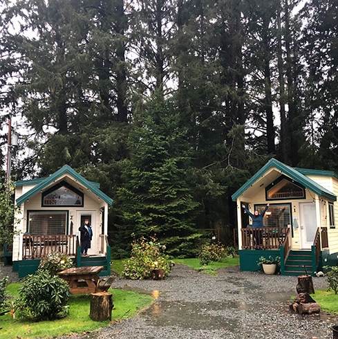 Photo of people standing in front of rustic cabins.